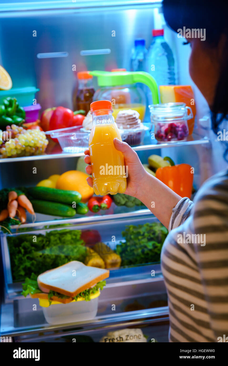 Femme prend le jus d'Orange de l'open réfrigérateur Banque D'Images