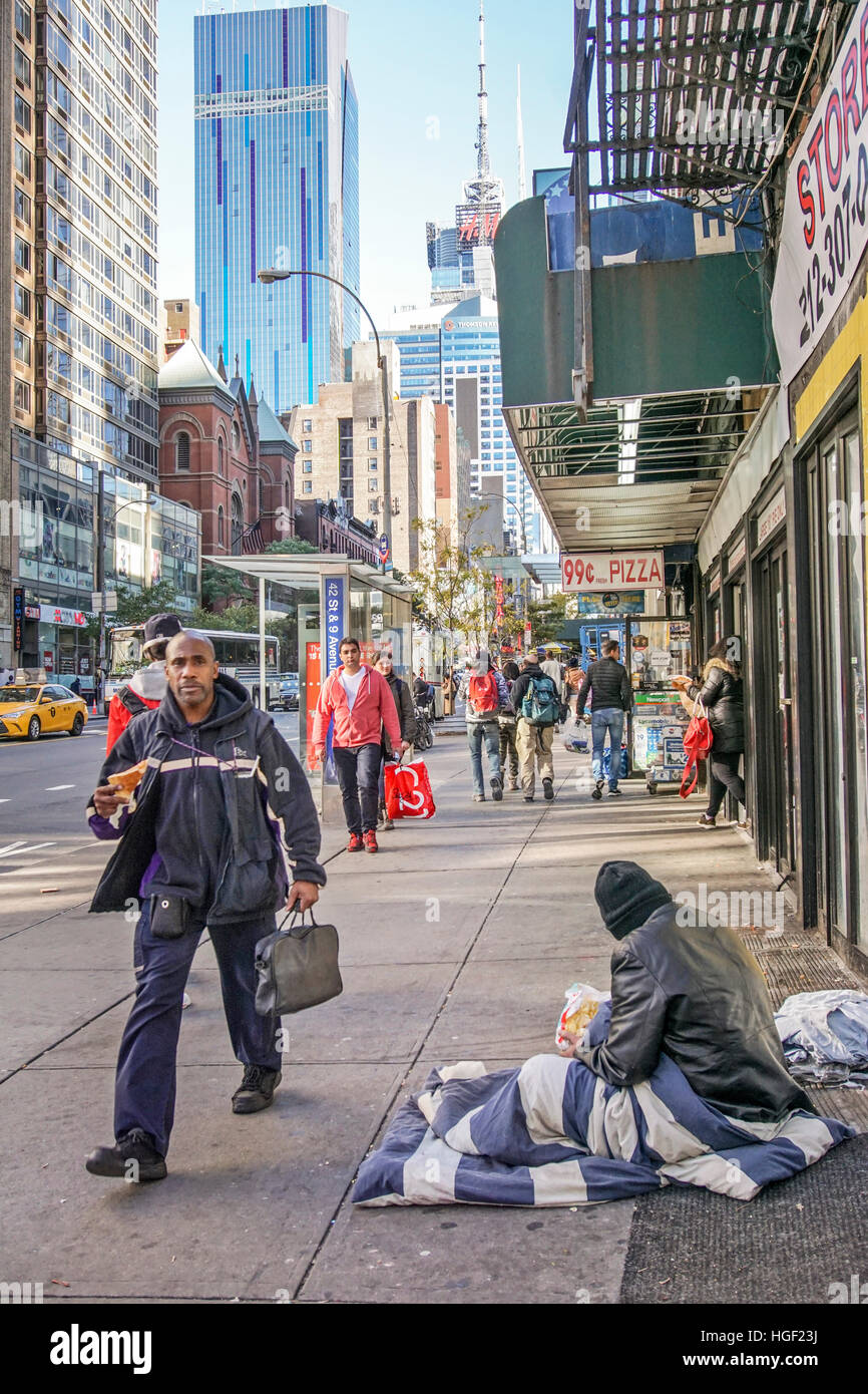 Homme mange pizza slice pas par personne sans-abri assis dans sac de couchage livré contre le froid sur le trottoir ouest 42e eating chips Banque D'Images