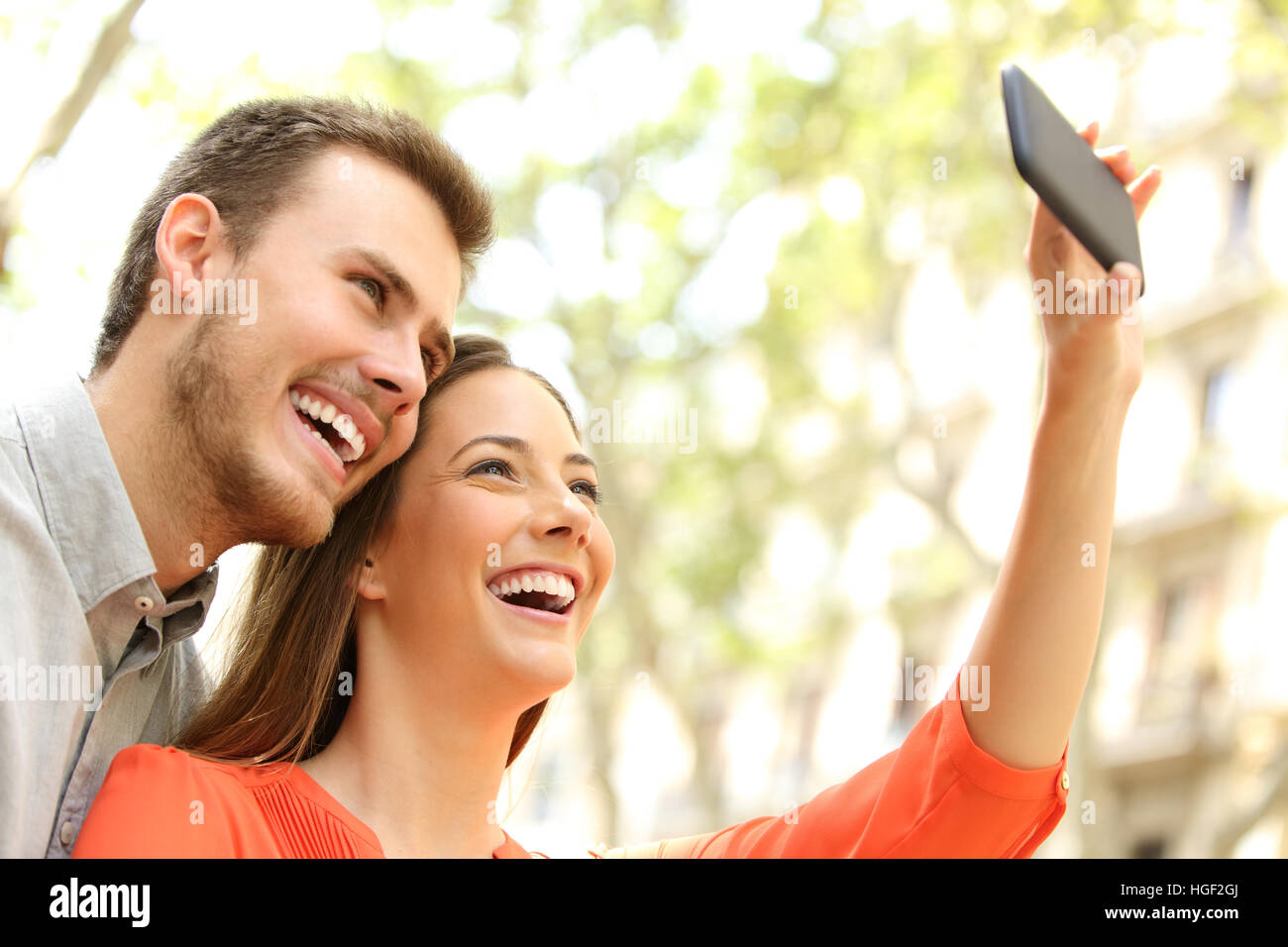 Casual couple heureux de prendre ou de photographier avec un selfies smart phone dans la rue Banque D'Images
