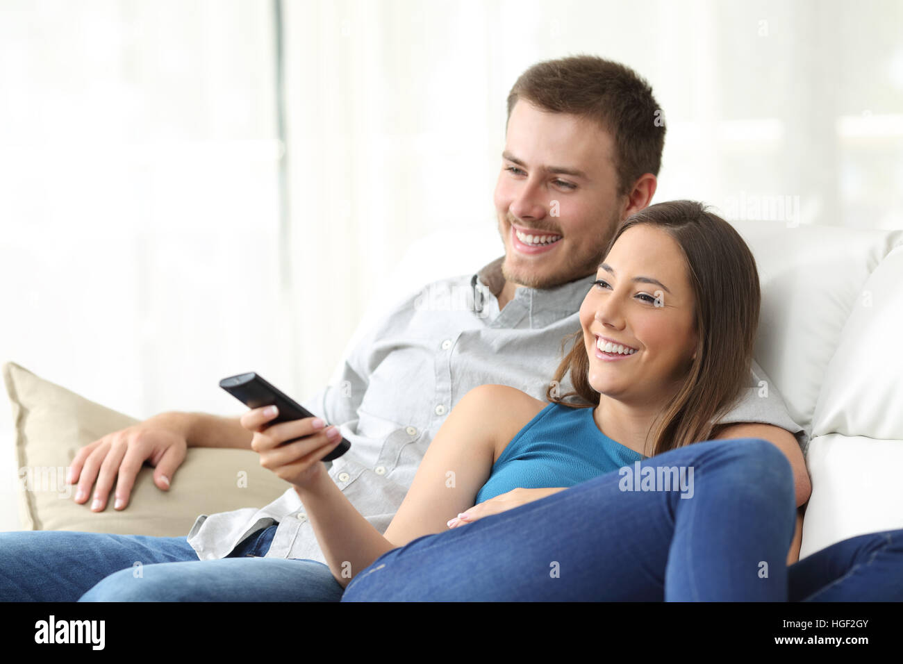 Heureux couple watching tv à la maison assis dans un confortable canapé dans le salon à la maison Banque D'Images