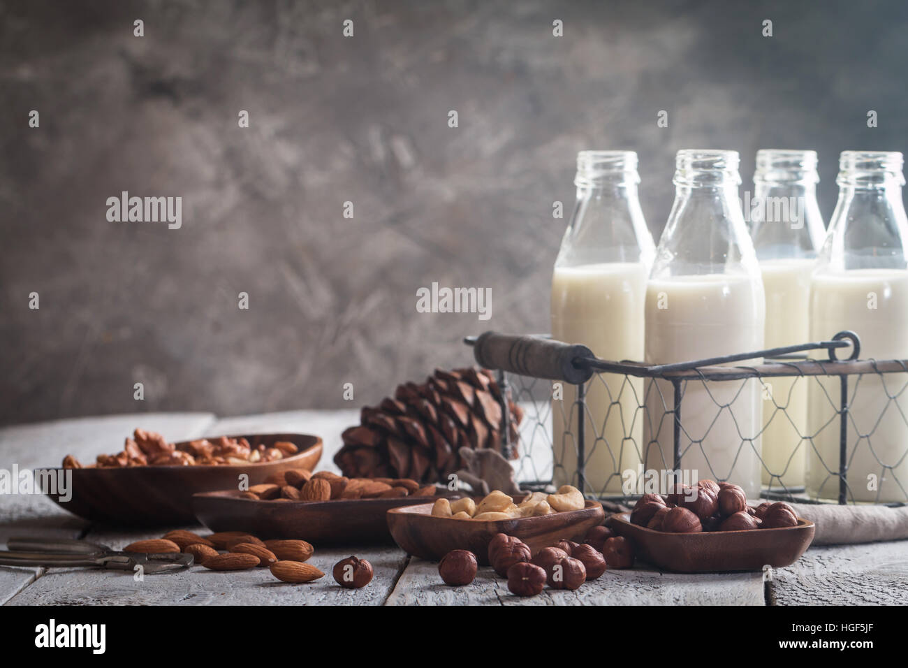 Lait de noix Vegan en bouteilles de verre avec différents écrous sur le vieux fond de bois Banque D'Images