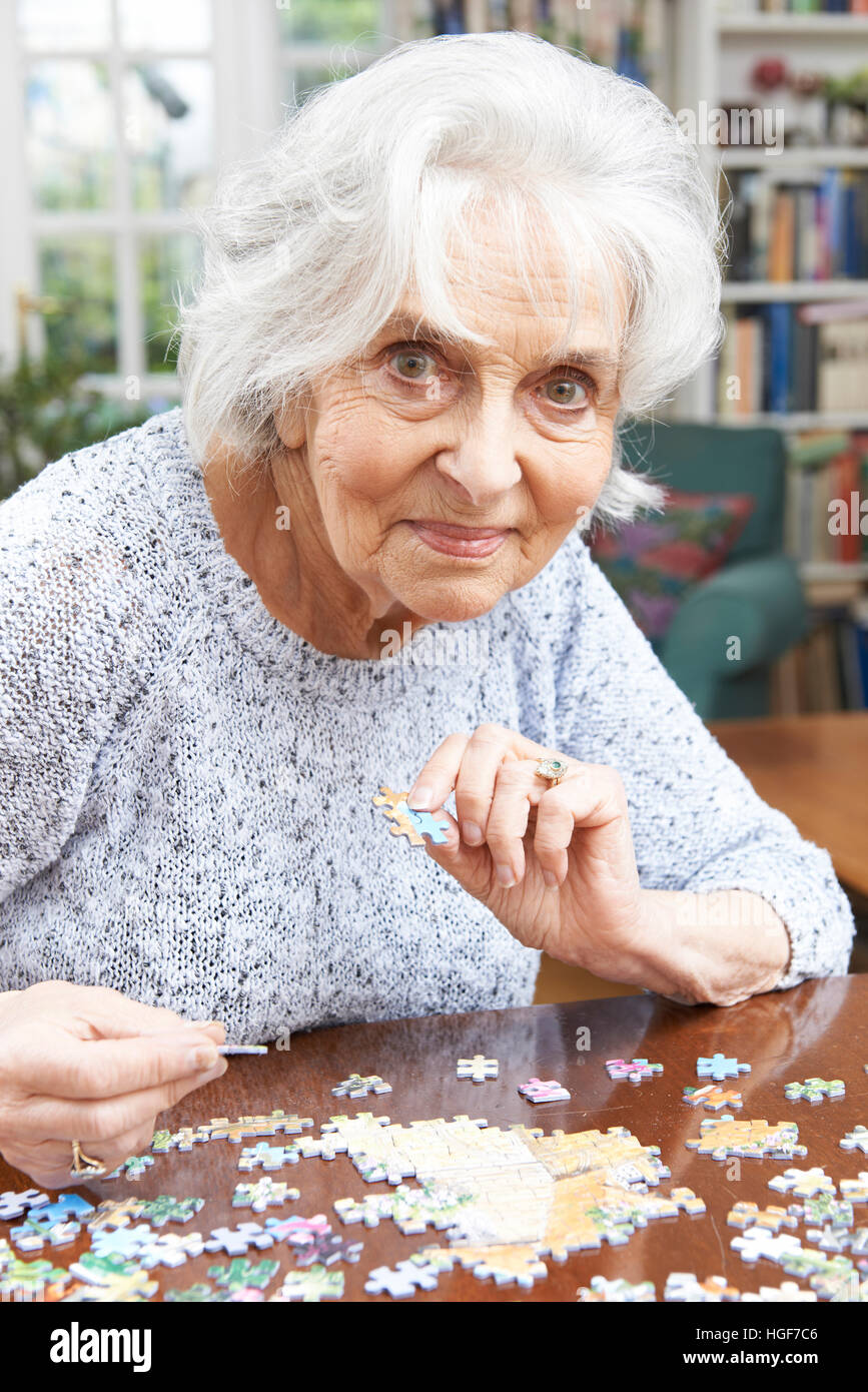 Senior Woman Relaxing With Jigsaw Puzzle à la maison Banque D'Images