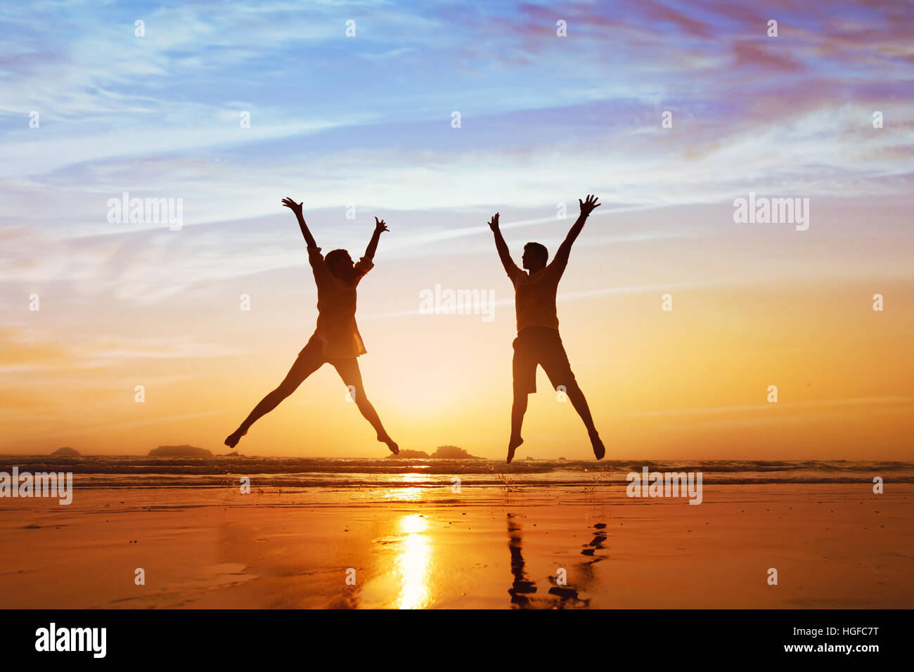 Couple heureux de sauter sur la plage au coucher du soleil, lune de miel ou des vacances en famille Banque D'Images