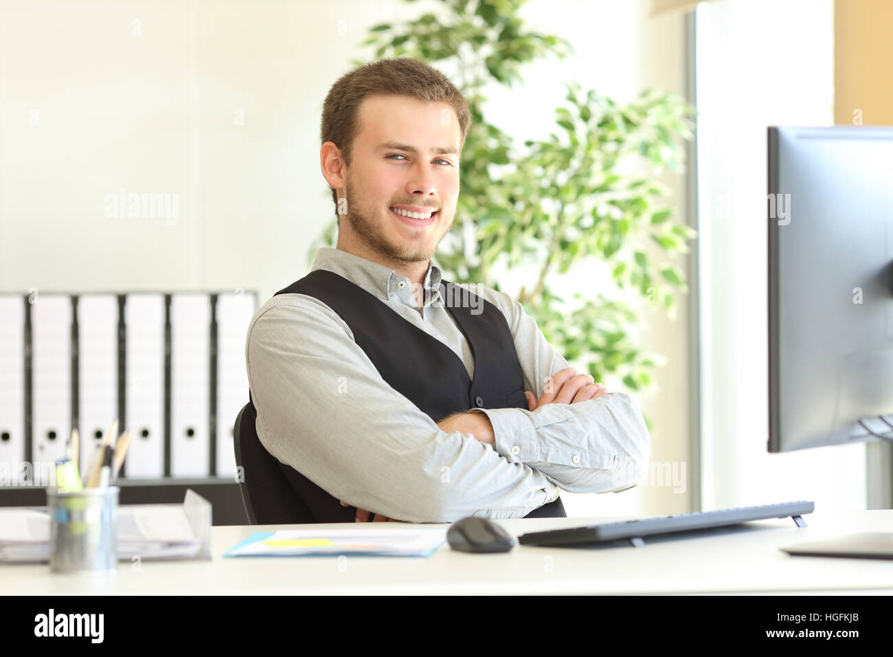 Fier businessman posing assis dans un bureau avec bras croisés dans son bureau et vous regarde Banque D'Images