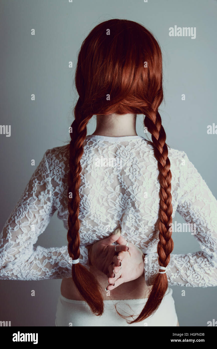 Jeune femme rousse avec deux longues tresses retour à l'appareil photo Banque D'Images