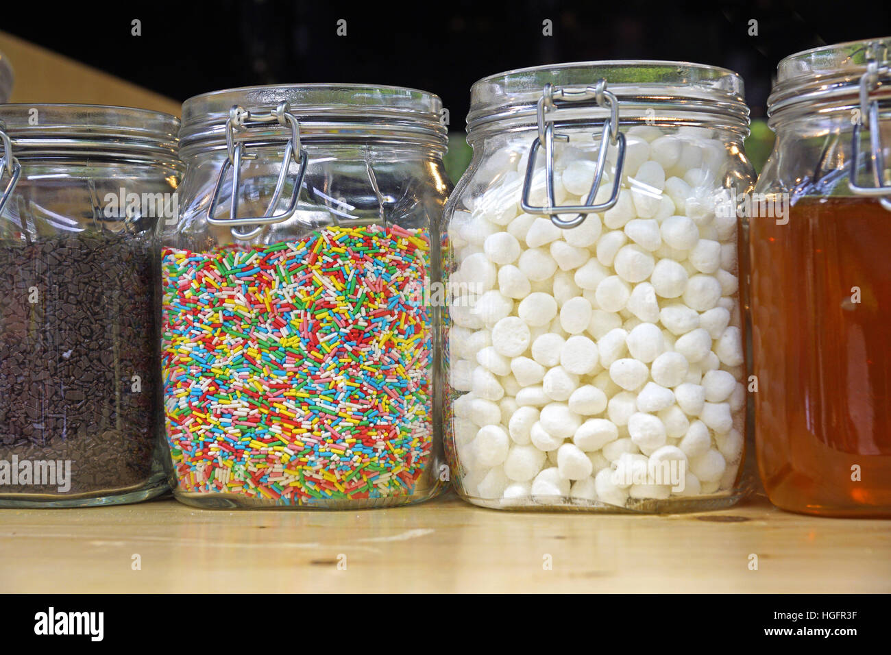 Bonbons colorés dans des bocaux sur fond de bois de table Banque D'Images