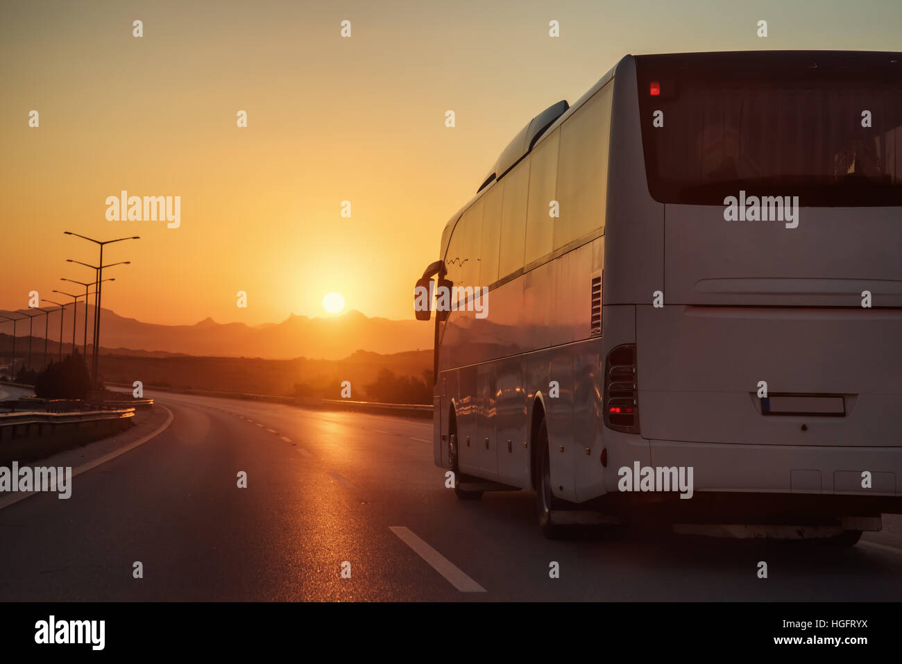 Autobus blanc de la conduite sur route vers le soleil couchant Banque D'Images