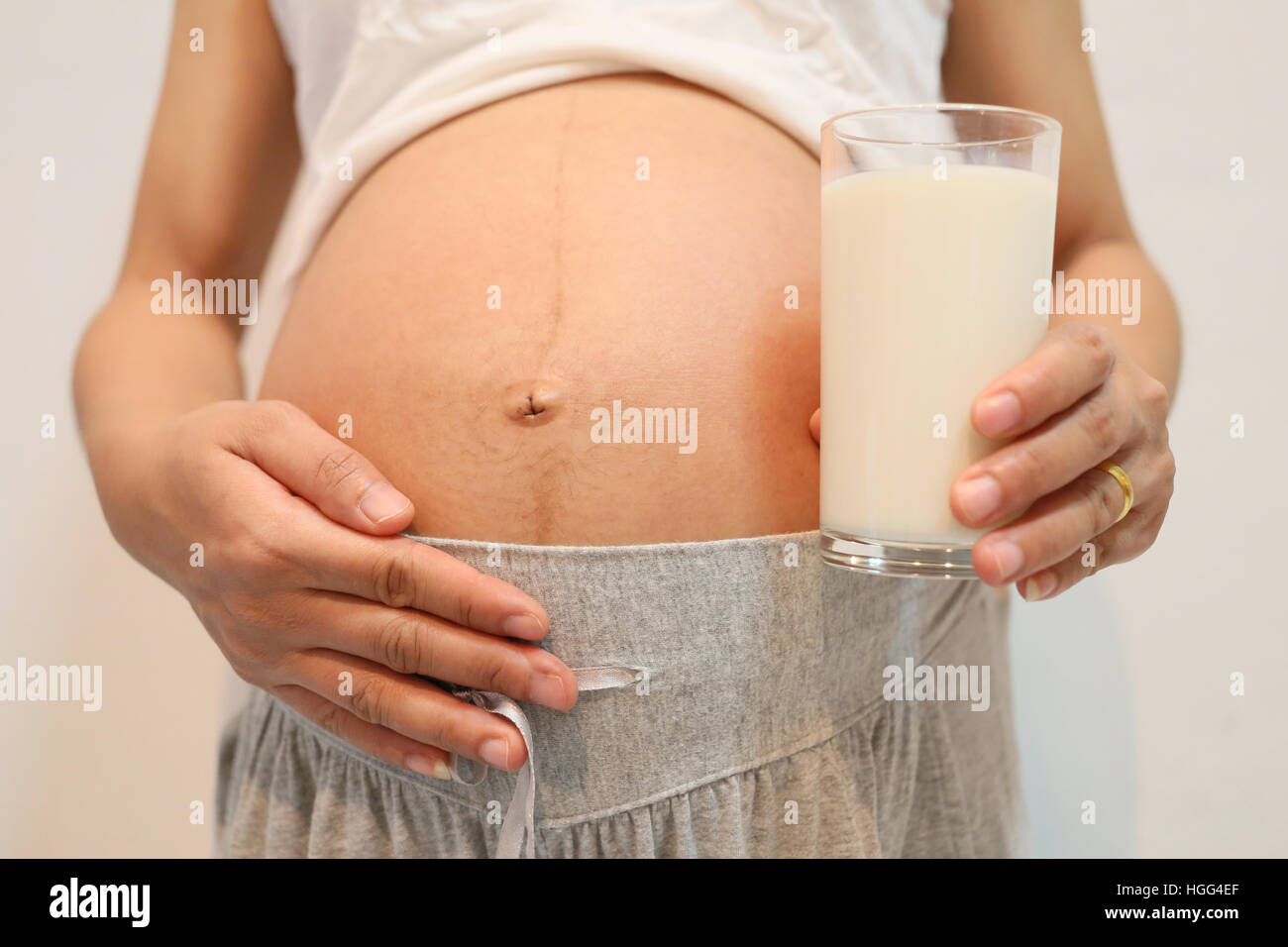 Les femmes enceintes en verre de lait hold de verre dans la main placée sur le ventre concept d'amour pour les aliments santé. Banque D'Images