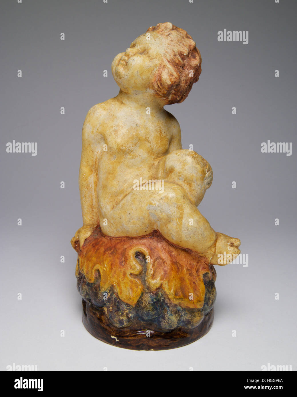 La figure de la Poterie Compton Bacchus assis sur la base d'un dôme de raisins et de feuilles de vigne. Le chiffre mesure 16cm de haut. Banque D'Images