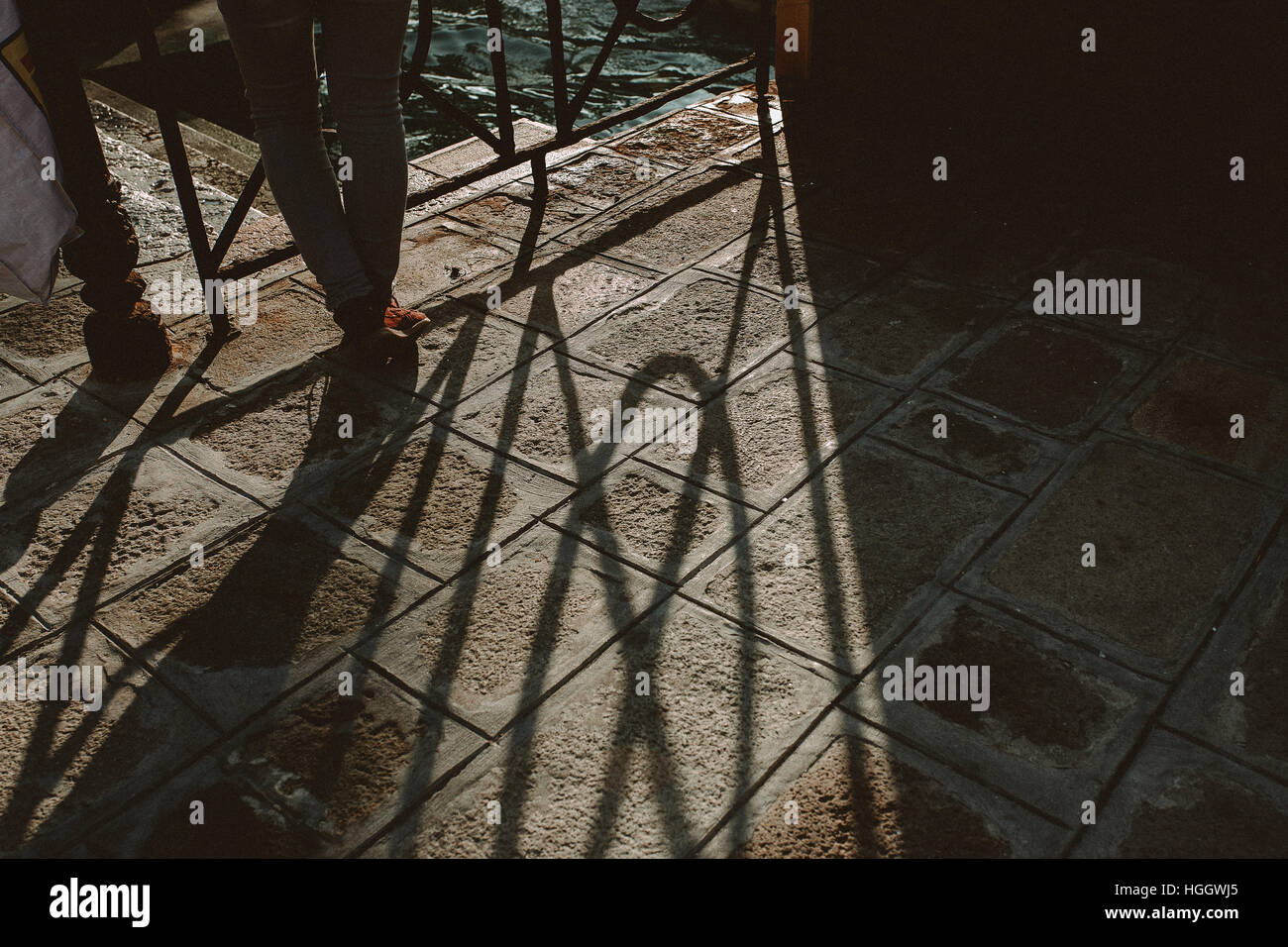 Une personne est leanin sur une balustrade. Le coucher du soleil crée une ombre sur le sol. La scène est tournée à Venise, Italie. Banque D'Images