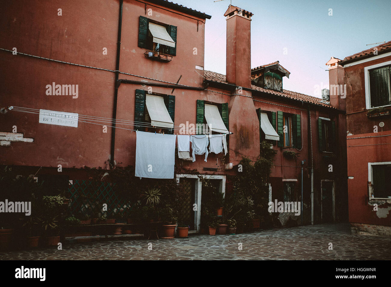 Une place avec maisons rouge de Venise, Italie. Le linge de maison est accrochée à la Windows. Banque D'Images
