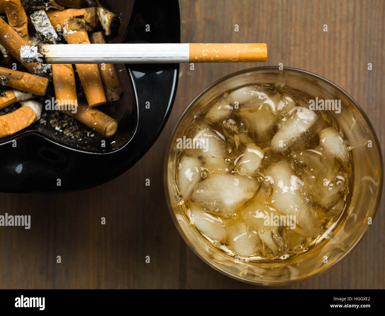 Verre de whisky écossais sur les rochers et d'une cigarette qui brûle dans un cendrier Banque D'Images
