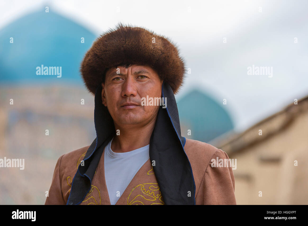 Homme kazakh en costume national avec les coupoles bleues de la mausolée de Khoja Ahmad Yasawi dans l'arrière-plan, Turkestan, Kazakhstan Banque D'Images