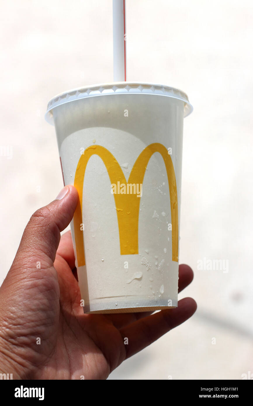 Close up of hand holding McDonald's soft drink dans la main gauche Banque D'Images