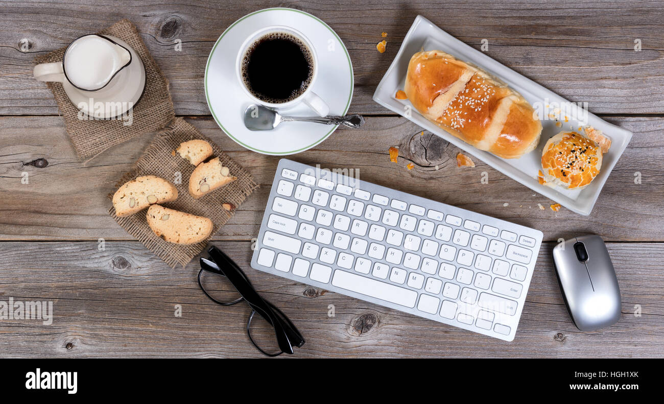 La technologie moderne et de repas du matin avec des pâtisseries fraîchement préparées avec du café et de la crème sur la table en bois rustique. Télévision mise en page. Banque D'Images