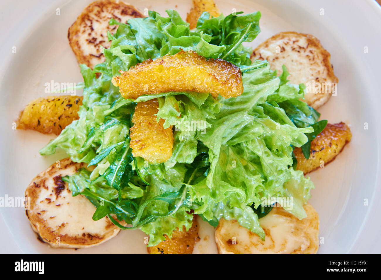 Avec la salade de roquette avec fromage frit et les tranches d'orange sur une table à manger Banque D'Images