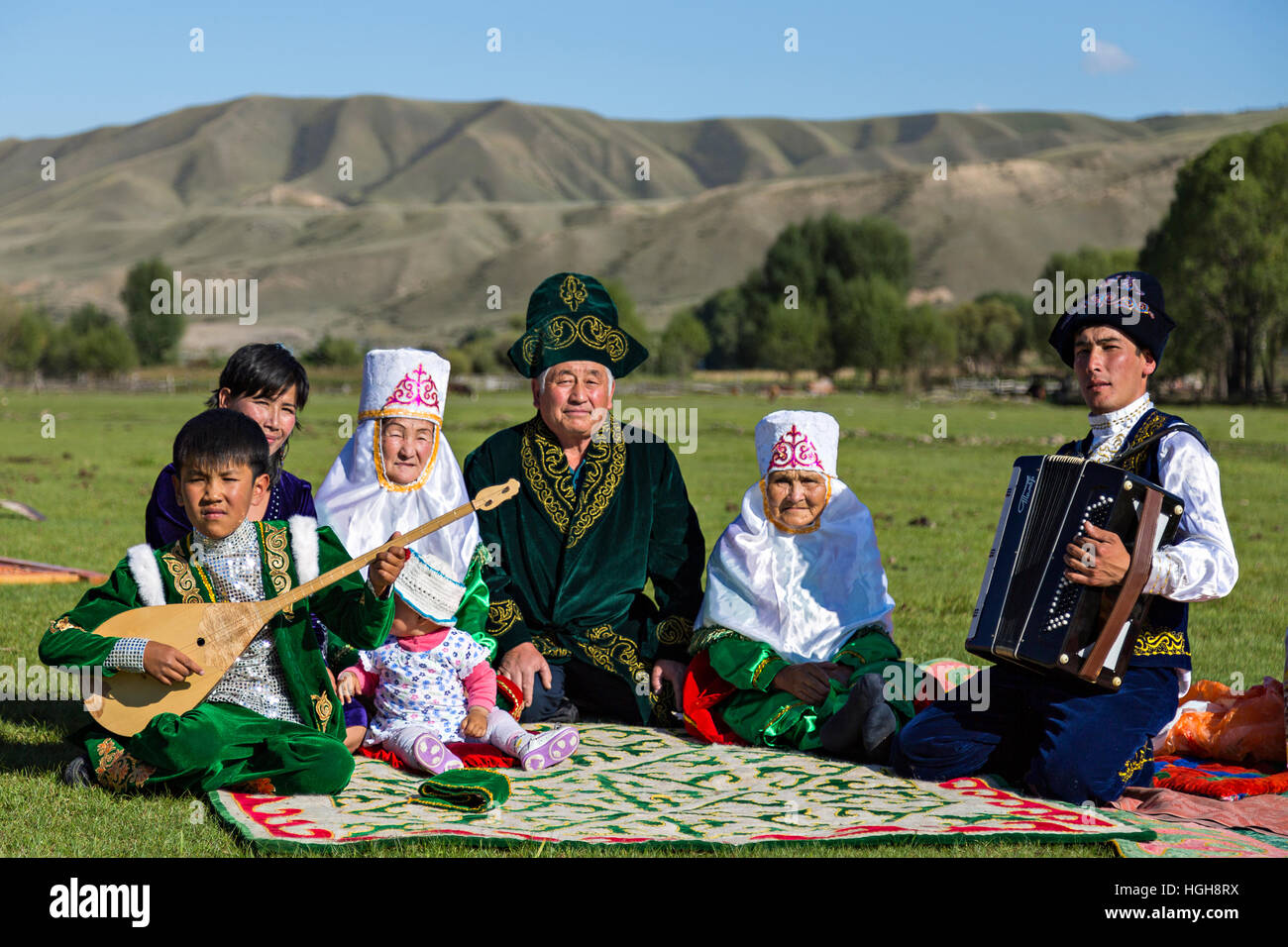 Famille du Kazakhstan, en costume national avec un homme à l'acordeon et un enfant jouant instrument local connu sous le nom de Dombra. Banque D'Images