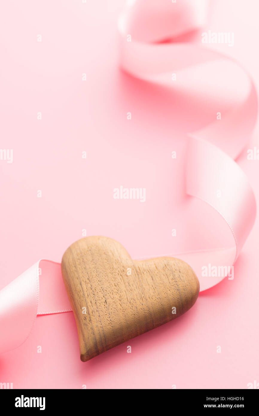 Coeur en bois et ruban rose sur fond rose. Banque D'Images