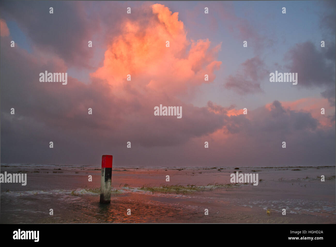 Plage avec plage rouge pôle, red clouds reflète dans la mer, au coucher du soleil Banque D'Images