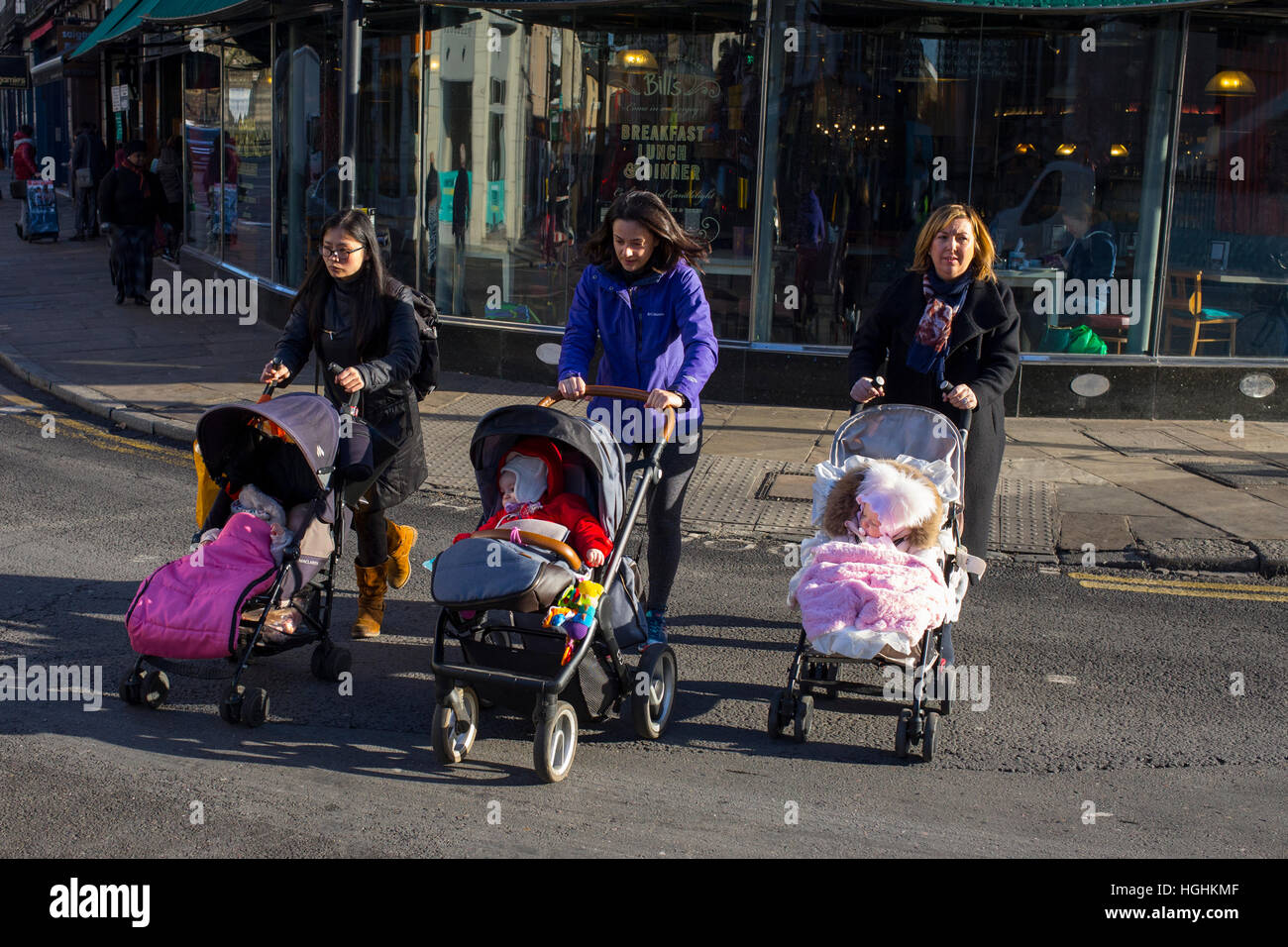 Femmes dehors marchant avec des enfants dans des poussettes Banque D'Images