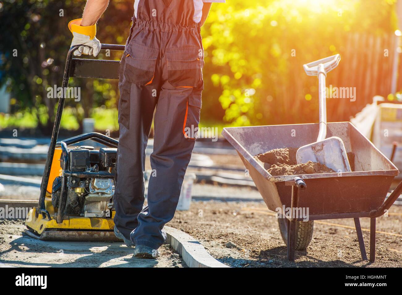 Chemin de brique de construction. Young Construction Worker with compacteur vibrant. Pavage en brique Thème. Banque D'Images