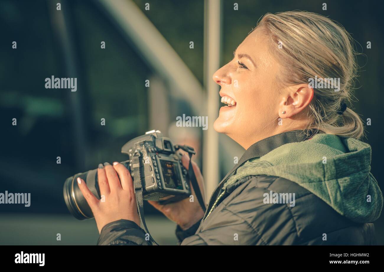 Heureux Femme photographe. Smiling Caucasian Woman avec appareil photo numérique professionnel en mains. La photographie passe-temps. Banque D'Images