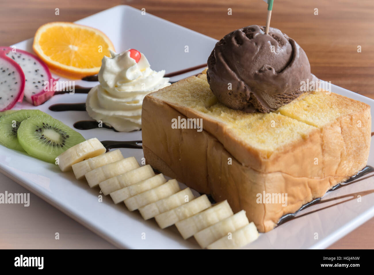 Toast au miel pain garni avec la crème glacée, chocolat sevred avec fruits et crème fouettée,couleur Banque D'Images