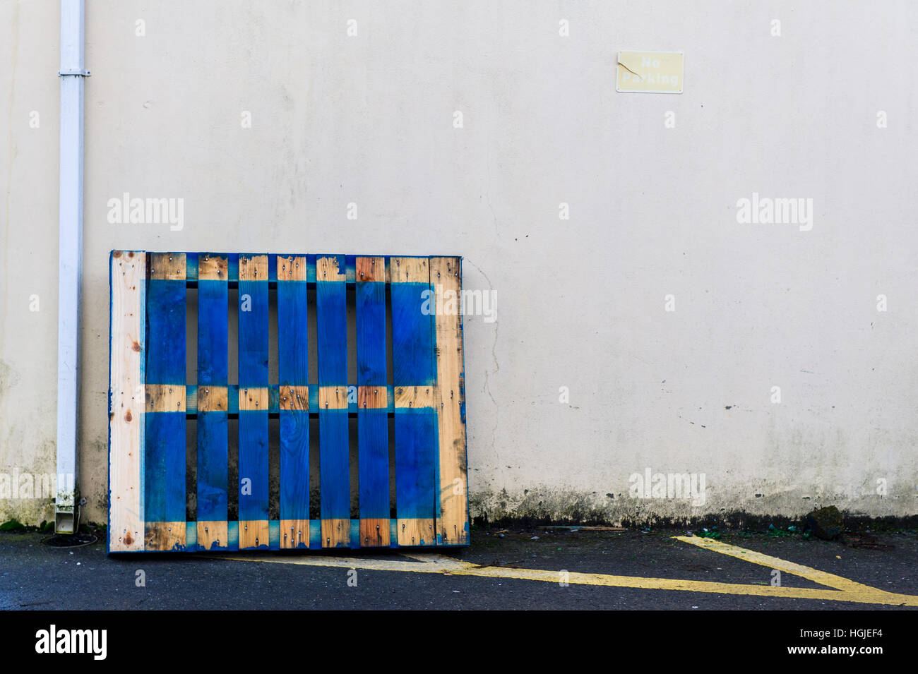 Palette en bois bleu appuyé contre un mur de béton blanc avec copie espace. Banque D'Images