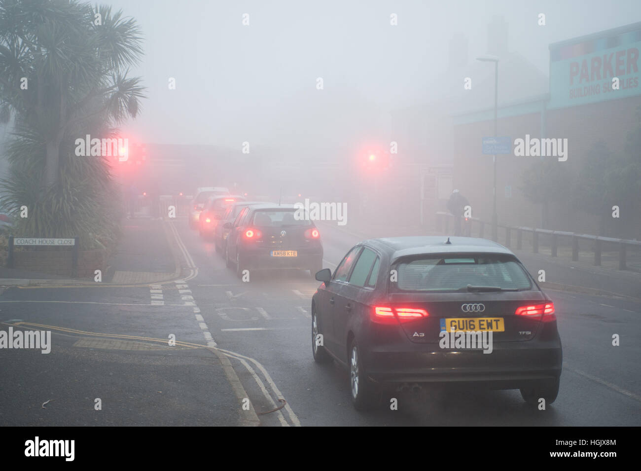 Un matin brumeux sur les voitures d'attente attendre dans une ligne de la circulation à un passage à niveau dans le West Sussex, Angleterre, Royaume-Uni. Banque D'Images