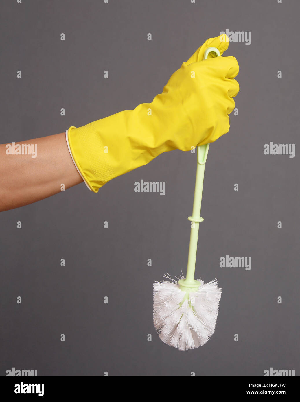 Une main gantée tenant une brosse de toilettes propres Banque D'Images