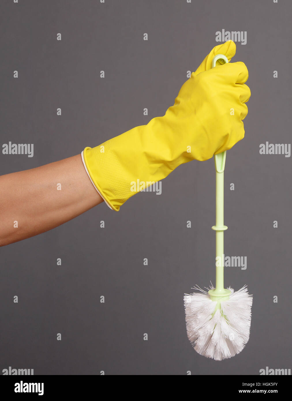 Une main gantée tenant une brosse de toilettes propres Banque D'Images