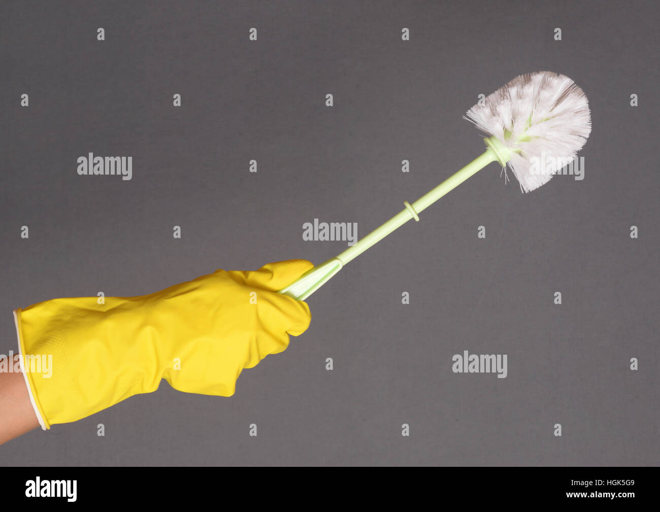 Une main gantée tenant une brosse de toilettes propres Banque D'Images