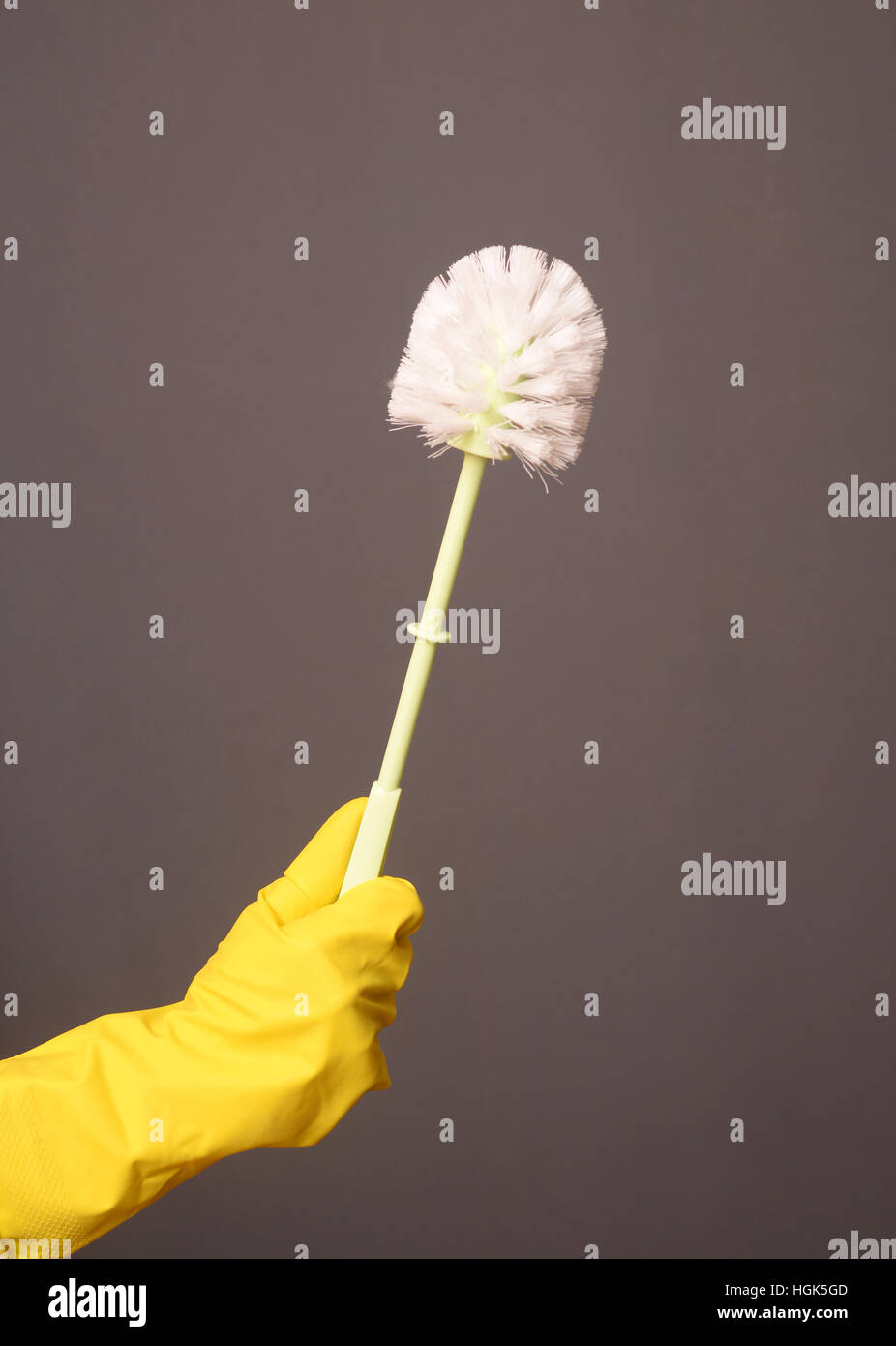 Une main gantée tenant une brosse de toilettes propres Banque D'Images