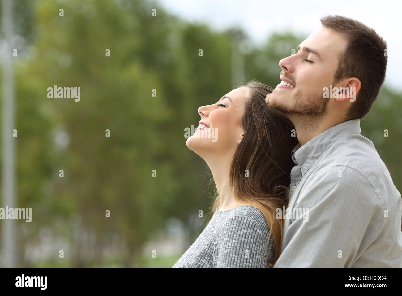 Vue de côté portrait d'un couple heureux, respirant l'air frais dans un parc avec des arbres verts dans l'arrière-plan Banque D'Images