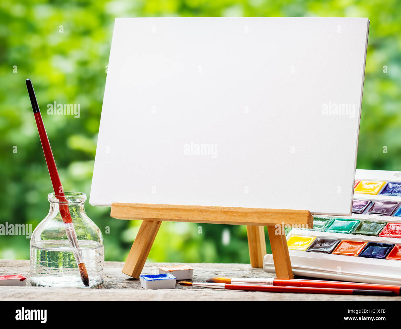 Sketchbook sur les peintures de chevalet, aquarelle, pinceaux artistiques et une bouteille d'eau sur la table à l'extérieur. Banque D'Images