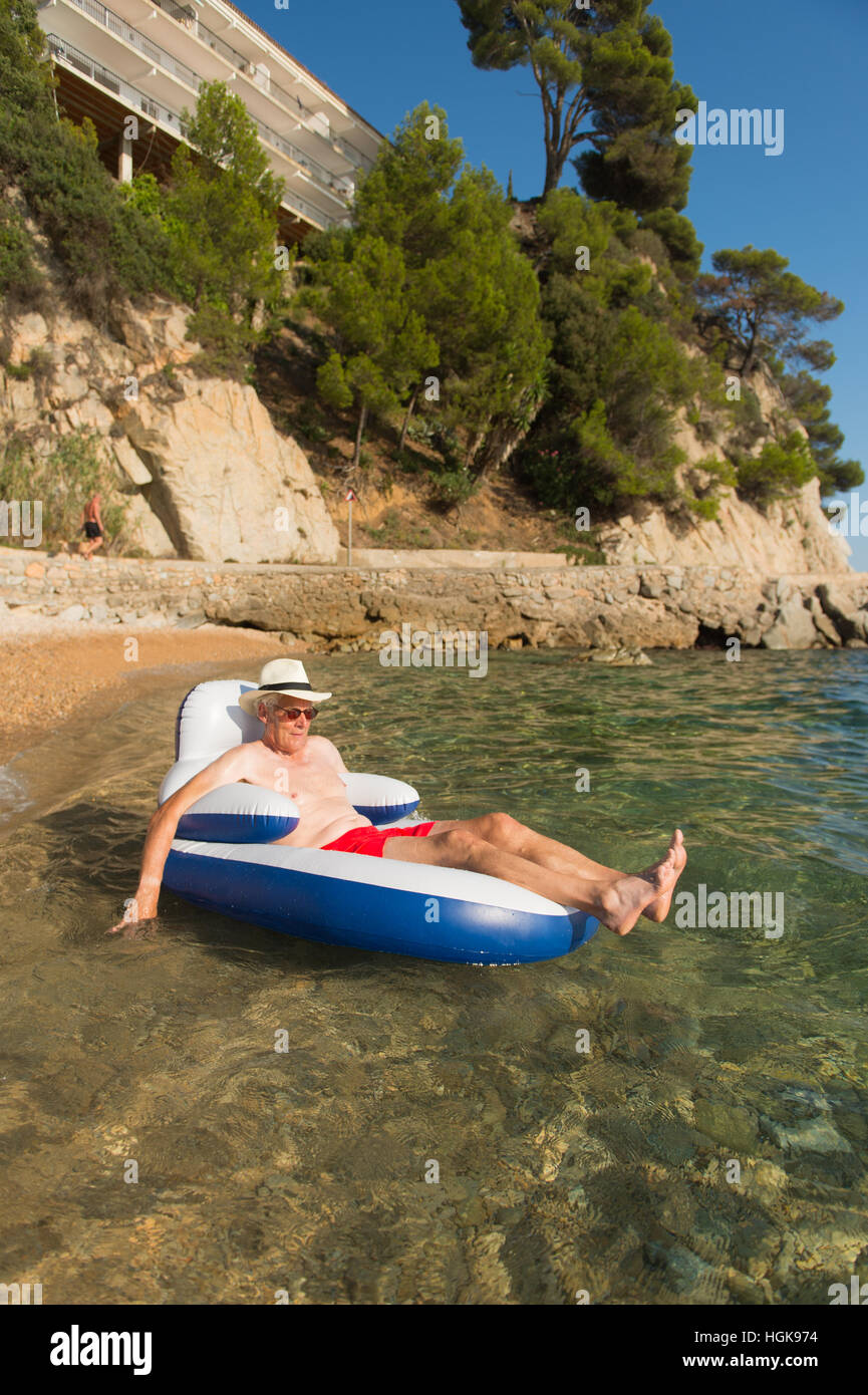 Senior en vacances flottant à la présidence dans la mer Banque D'Images