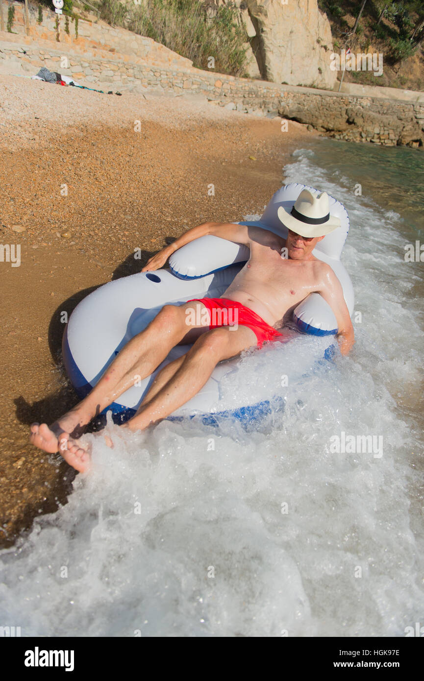 Senior en vacances flottant à la présidence dans la mer Banque D'Images