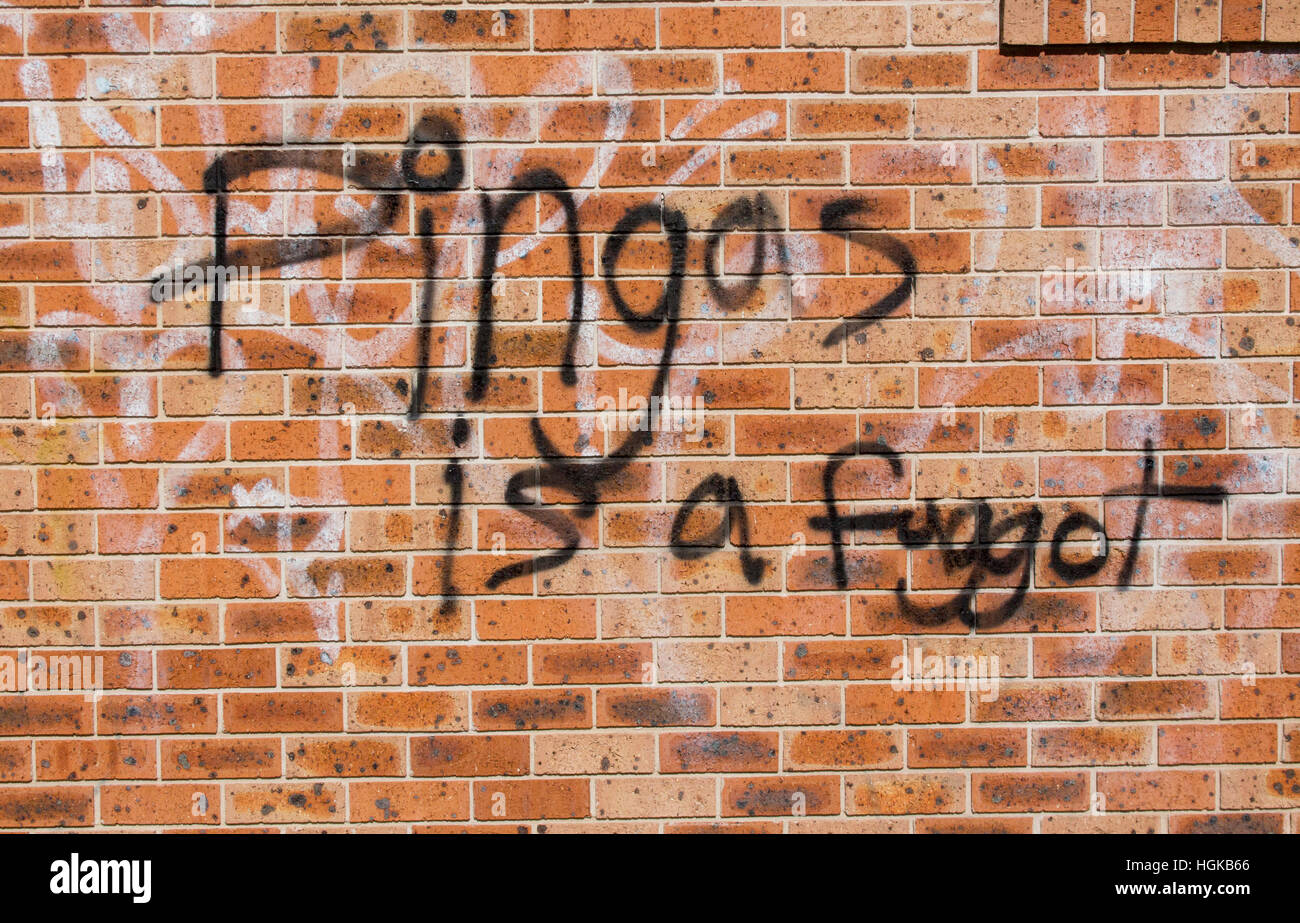 Graffitis homophobes par les mots 'Pingas est un pédé" peint en noir sur un mur de brique rouge Banque D'Images