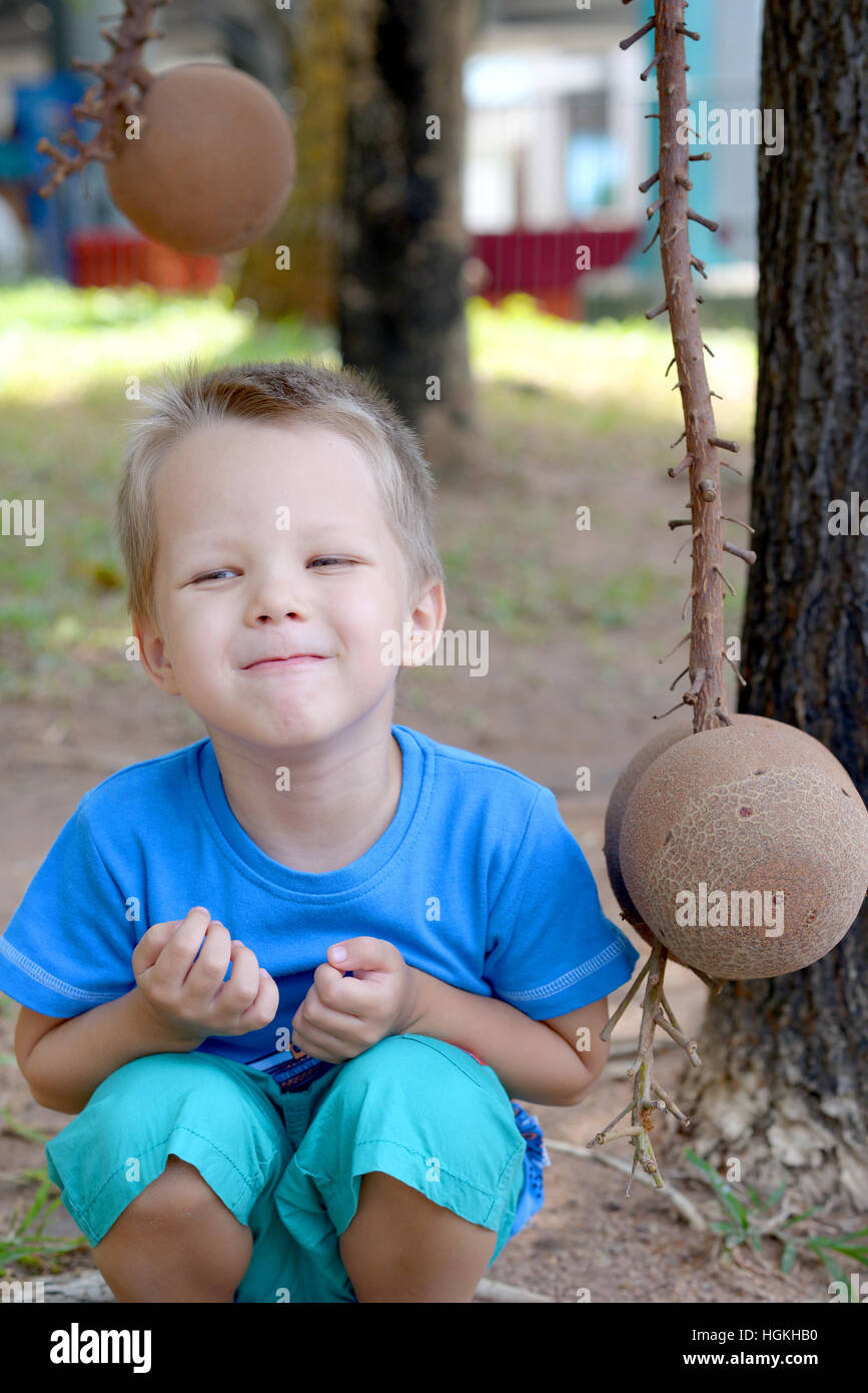 Repos de l'enfant près de cocotier dans un jardin tropical Banque D'Images