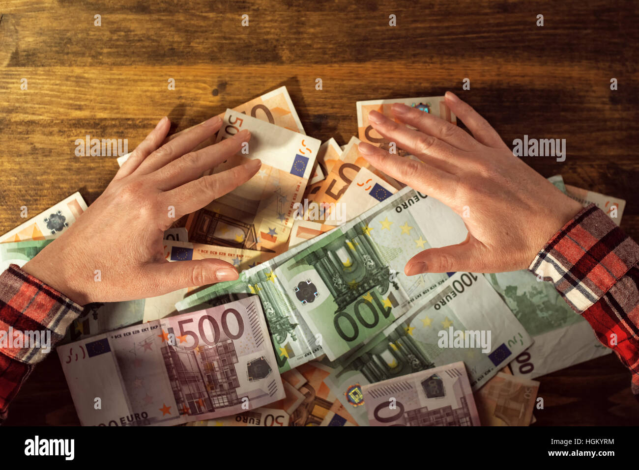 Les mains avides de retrait du tas de billets en euros cash money sur office 24 Banque D'Images