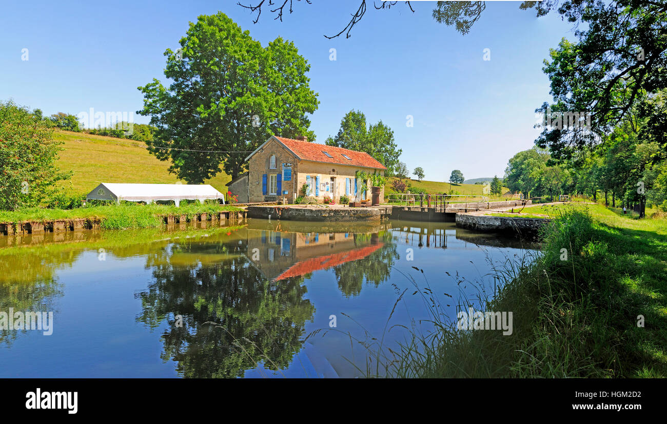 Serrure sur le canal de Dijon en Bourgogne avec la réflexion de maison éclusière dans le canal. Banque D'Images
