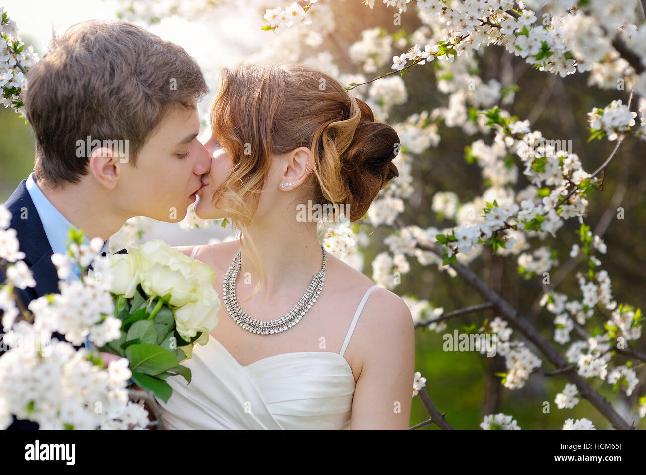 Mariés à la baiser de mariage au printemps à pied Park Banque D'Images