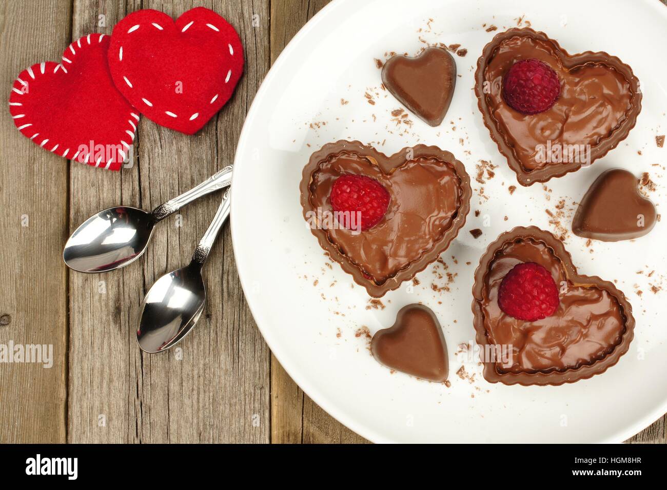 Chocolat en forme de coeur avec des coupes à dessert au lait et framboises sur plaque avec fond en bois Banque D'Images