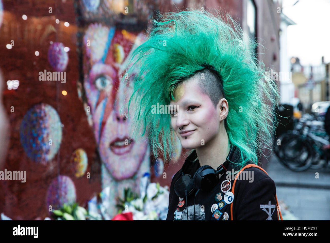 Londres, Royaume-Uni. 10 janvier, 2017. Une fille avec une coupe mohican vert rend hommage à David Bowie en face d'une peinture murale à Brixton sur le premier anniversaire de sa mort. Credit : Mark Kerrison/Alamy Live News Banque D'Images