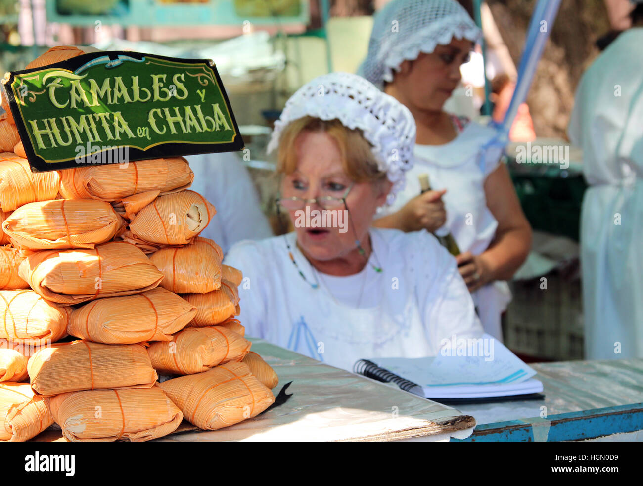 Femme en bonnet vend à la Feria de Mataderos tamales Banque D'Images