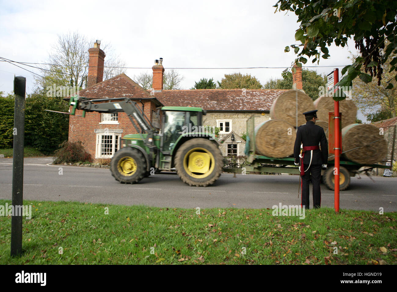 Un homme militaire attend patiemment pour un tracteur pour passer à côté d'un arrêt de bus du village en Angleterre Banque D'Images