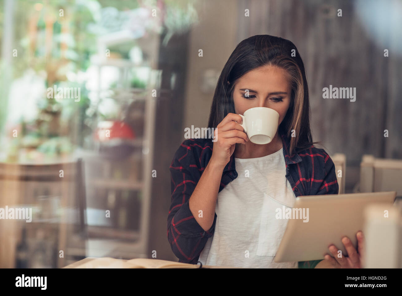 Jeune femme à l'aide d'une tablette numérique à son café préféré Banque D'Images