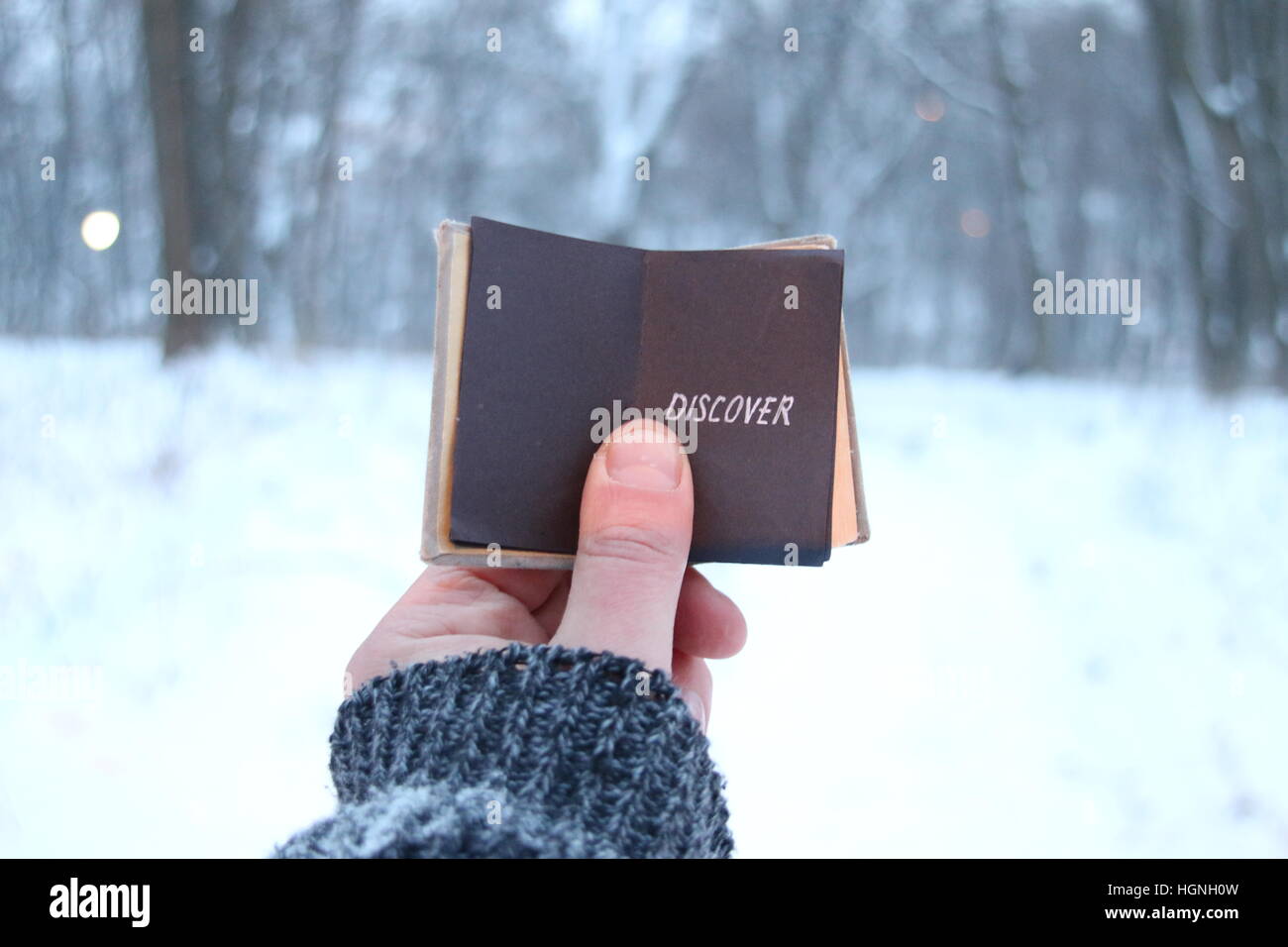 Découvrez concept, traveler tient un livre dans sa main avec l'inscription à l'arrière-plan de la forêt d'hiver Banque D'Images