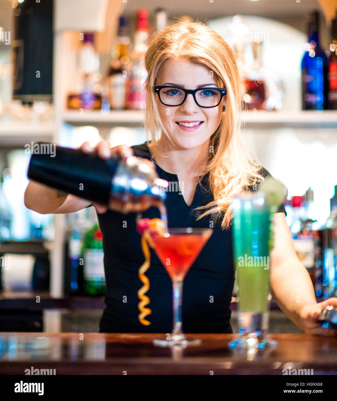 Une serveuse de servir un cocktail dans un bar looking at camera Banque D'Images