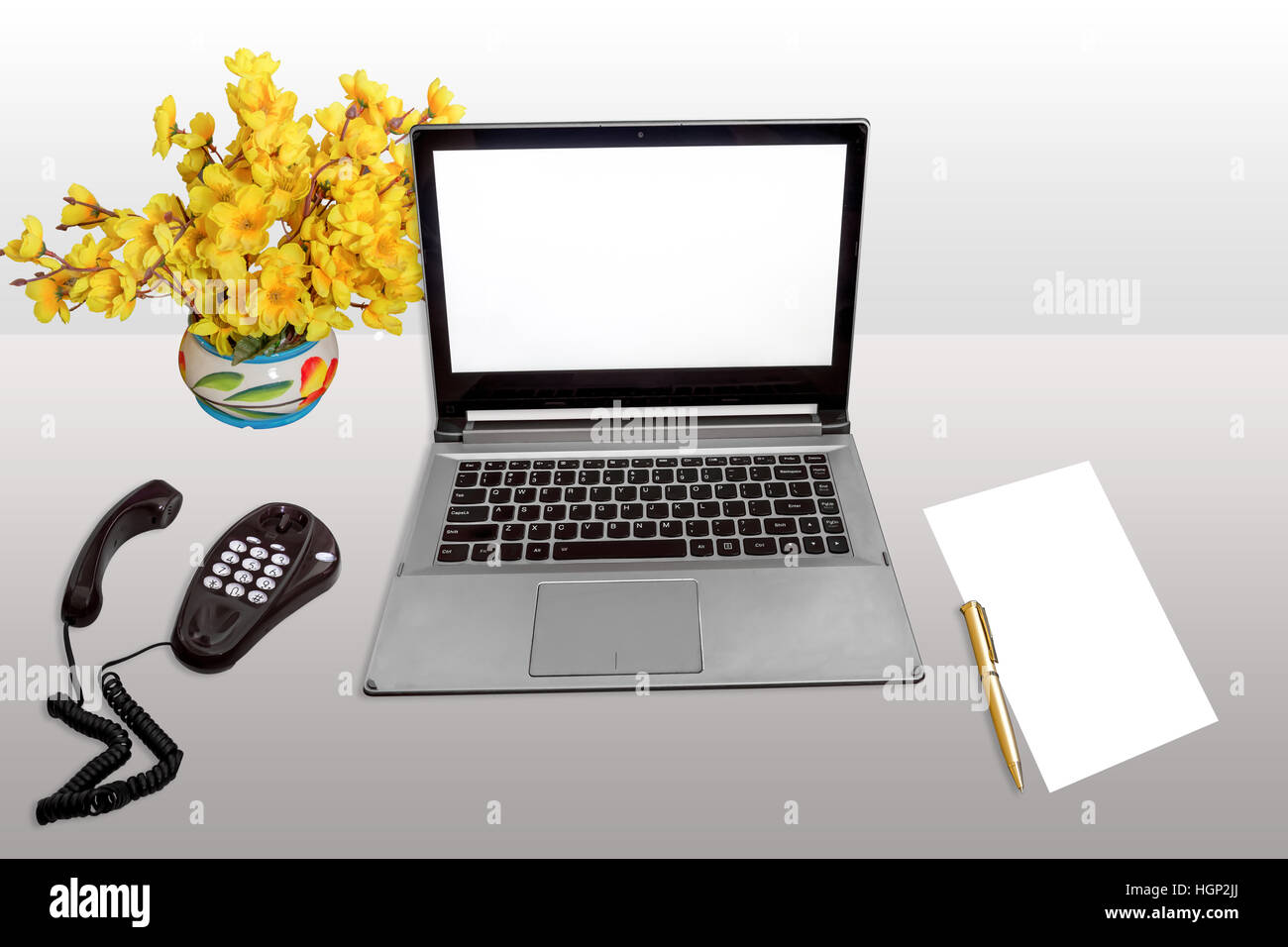 Lieu de travail avec ordinateur portable écran blanc, téléphone de bureau, de papier vierge et un stylo blanc isolé. Banque D'Images